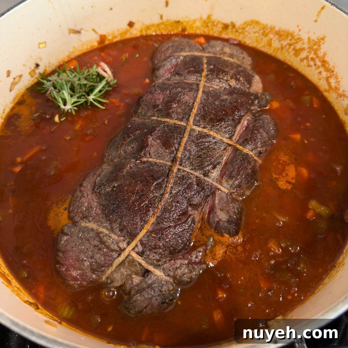 Pot roast added to a pot of broth, reduce wine and vegetables for cooking.