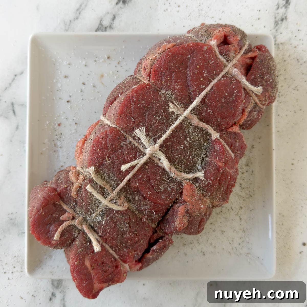 A tied raw chuck roast ready for seasoning and cooking.
