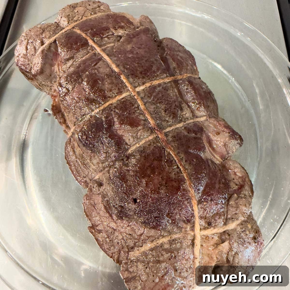 A nicely browned roast of beef on a plate waiting for next steps in the process.