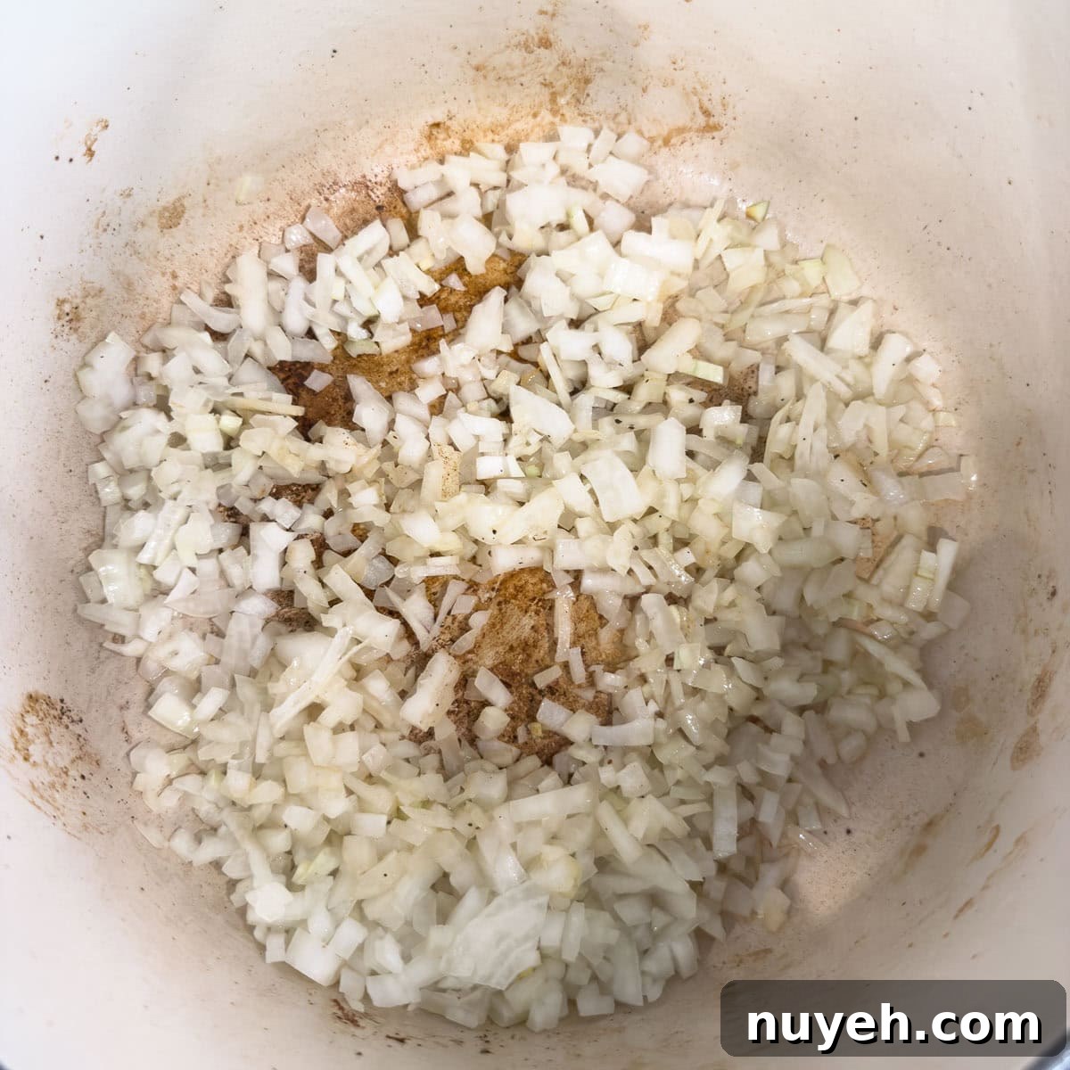 Chopped onion sautéing in a pot in olive oil.