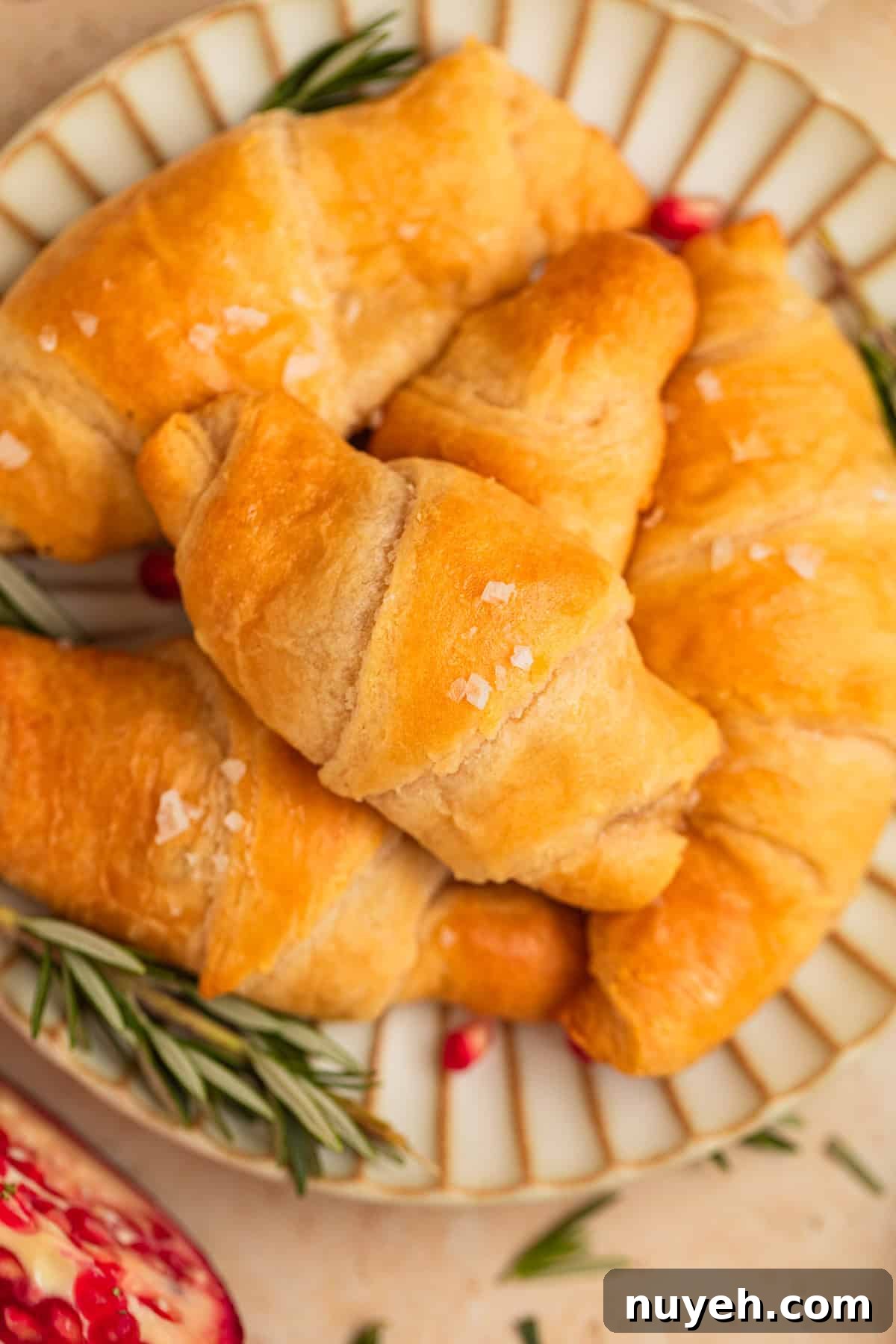 Pomegranate, brie and rosemary stuffed crescent rolls on plate.
