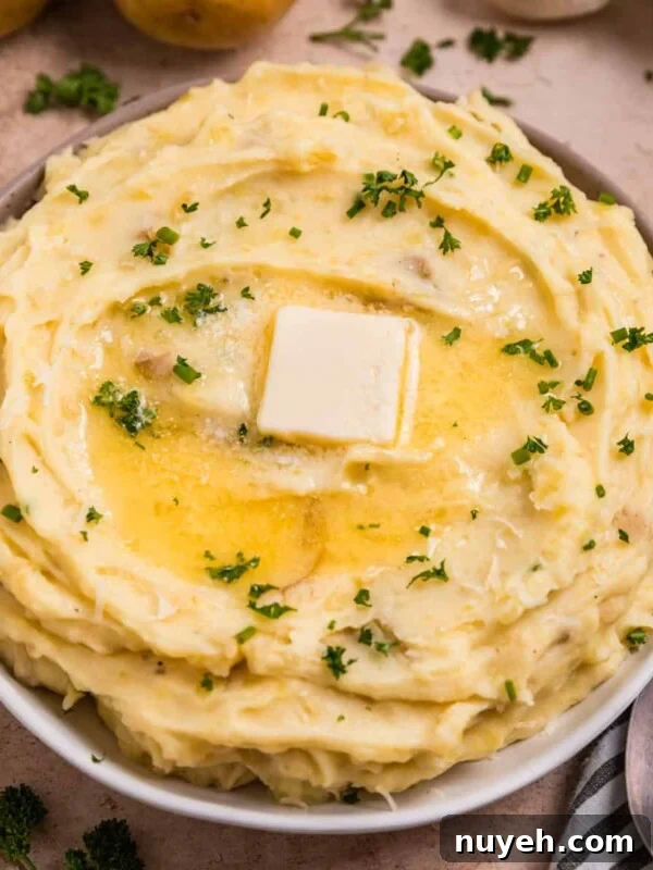 Garlic parmesan mashed potatoes in serving dish with melted butter over top.