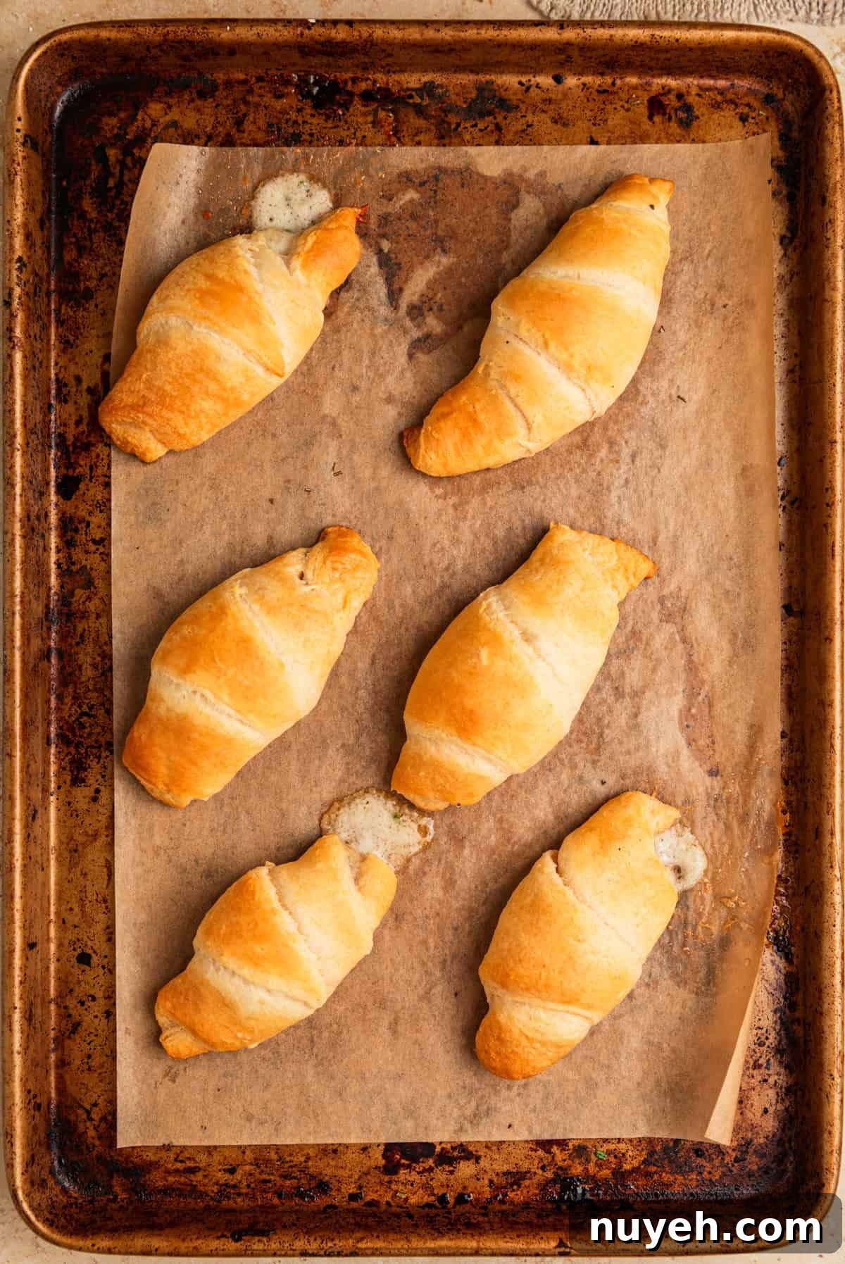 Baked stuffed crescent rolls parchment lined baking sheet.