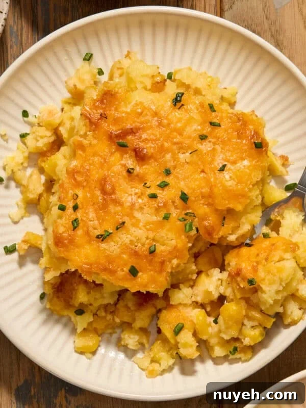 Cheesy cornbread casserole on white dish with fork scooping in.
