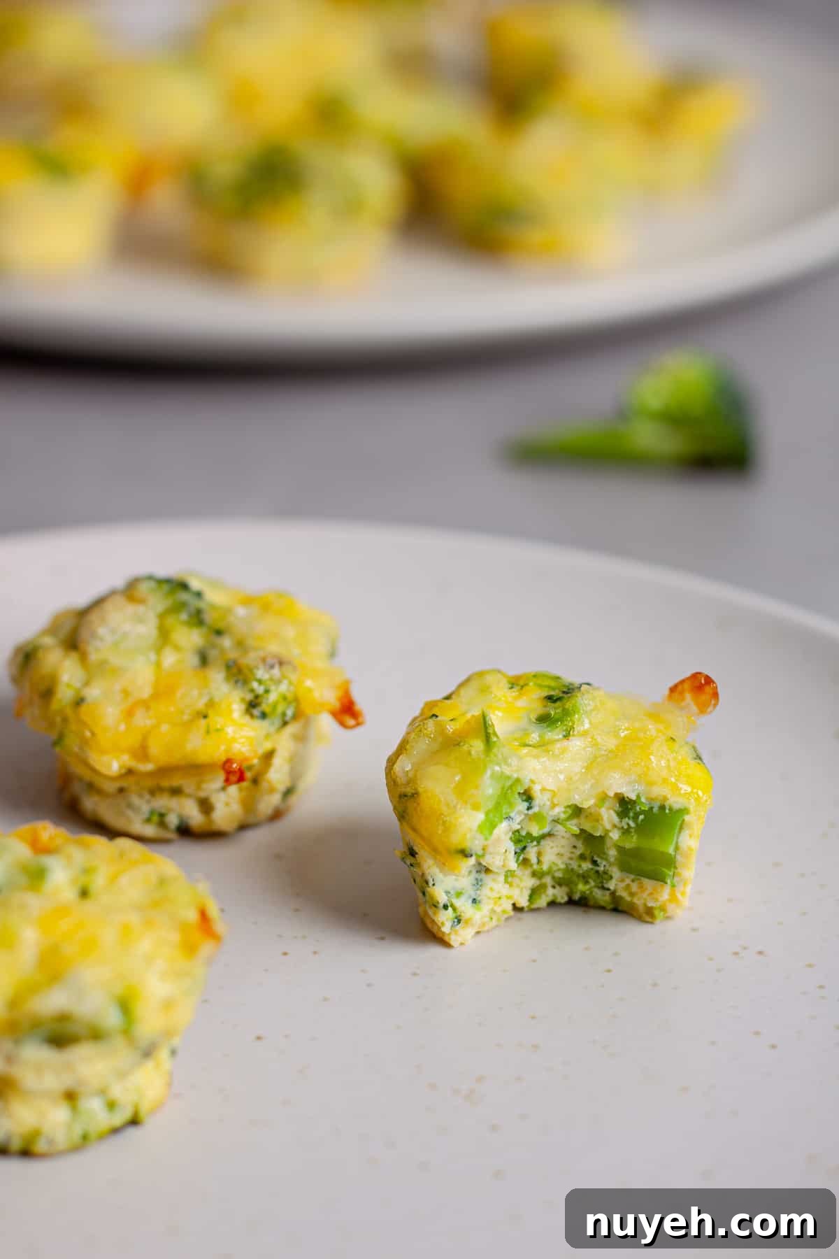 A small plate of mini egg bites and one has a bite taken out of it.