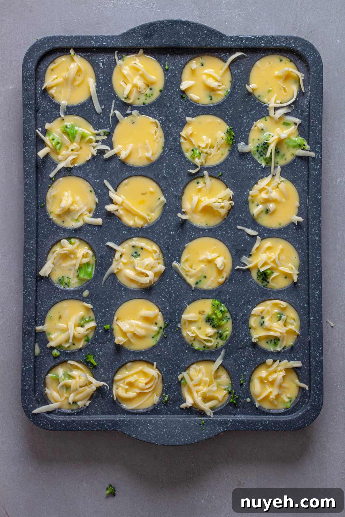 Mini egg bites getting assembled in a mini muffin pan.