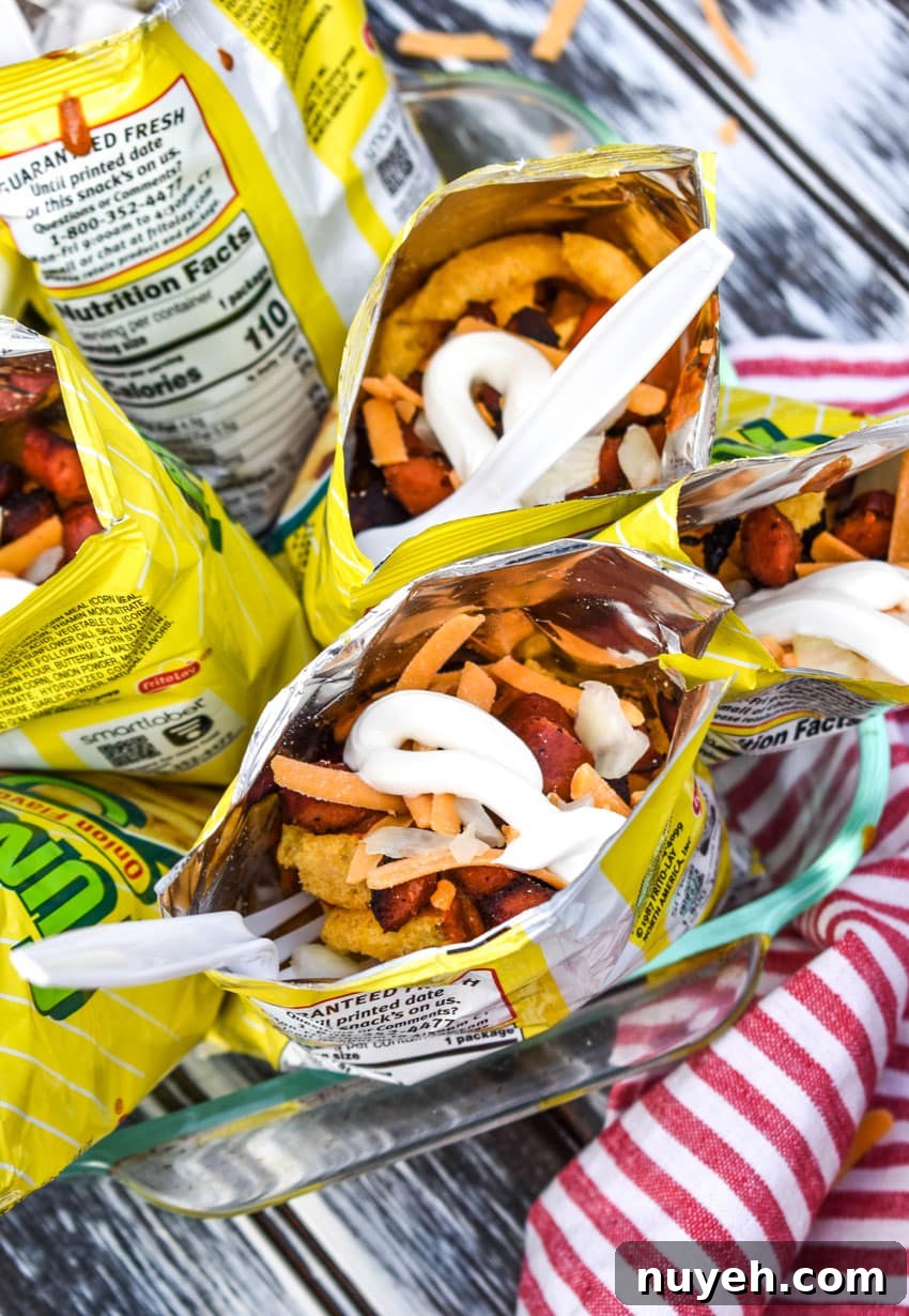 walking chili dogs arranged in a glass dish with white plastic forks stuck in them