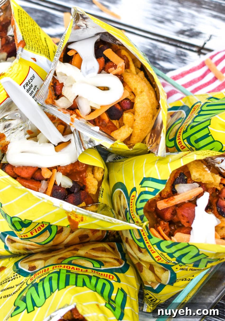 walking chili dogs arranged in a glass dish with white plastic forks stuck in them