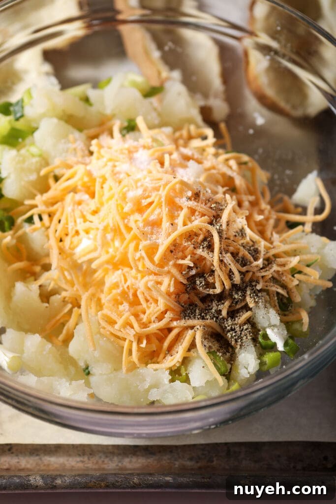 Cheese, sour cream, green onions, potato and more in a bowl before mixing