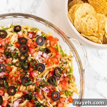 7 layer taco dip next to a bowl of tortilla chips