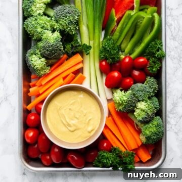 a top down view of a platter of veggies with a bowl of curry dip on it.