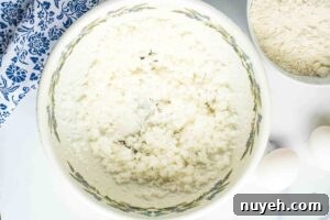 A bowl of crumbly, dry ingredients with lemon zest, ready to be mixed into a batter, highlighting the initial steps of making lemon bread.