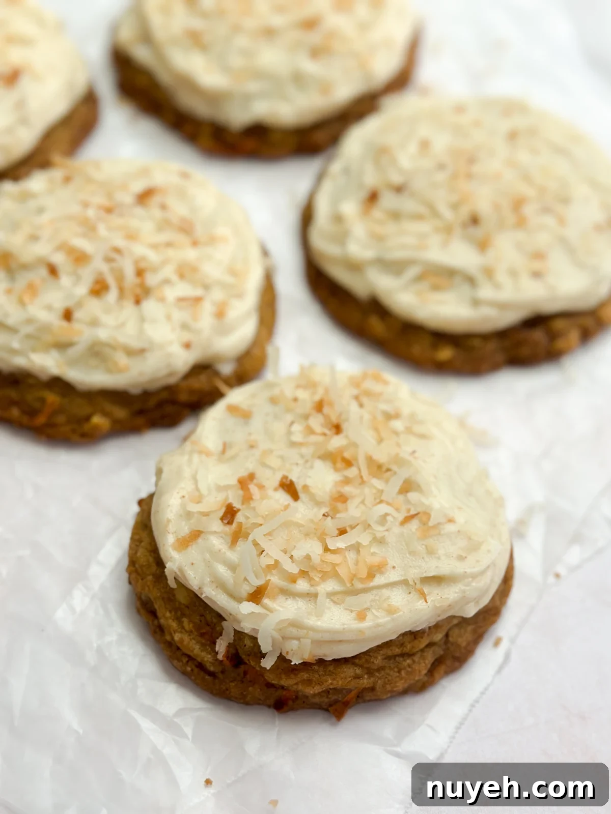 A side view of a chewy carrot cake cookie showing the frosting and coconut on top.
