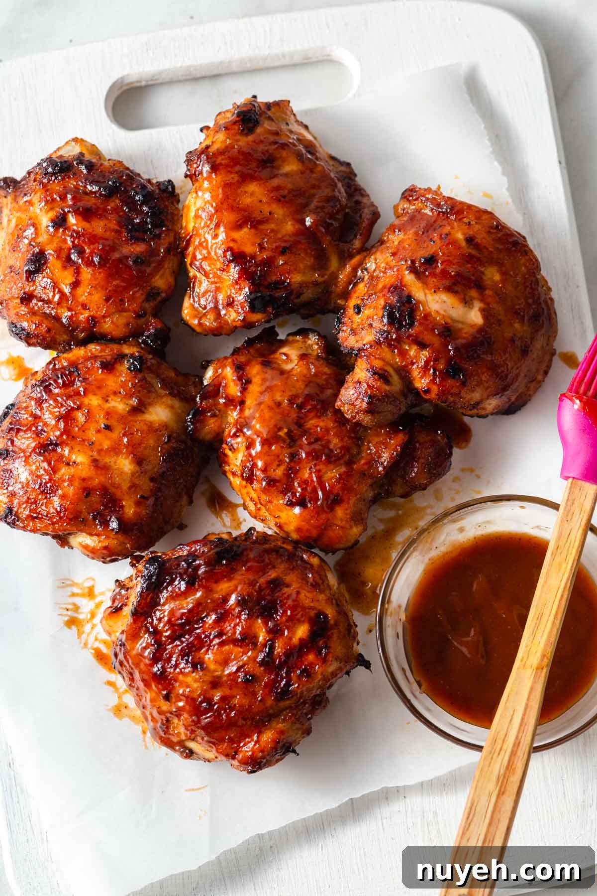 air fryer bbq chicken thighs with bbq sauce on a board.