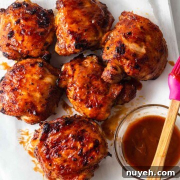 air fryer bbq chicken thighs with bbq sauce on a board.