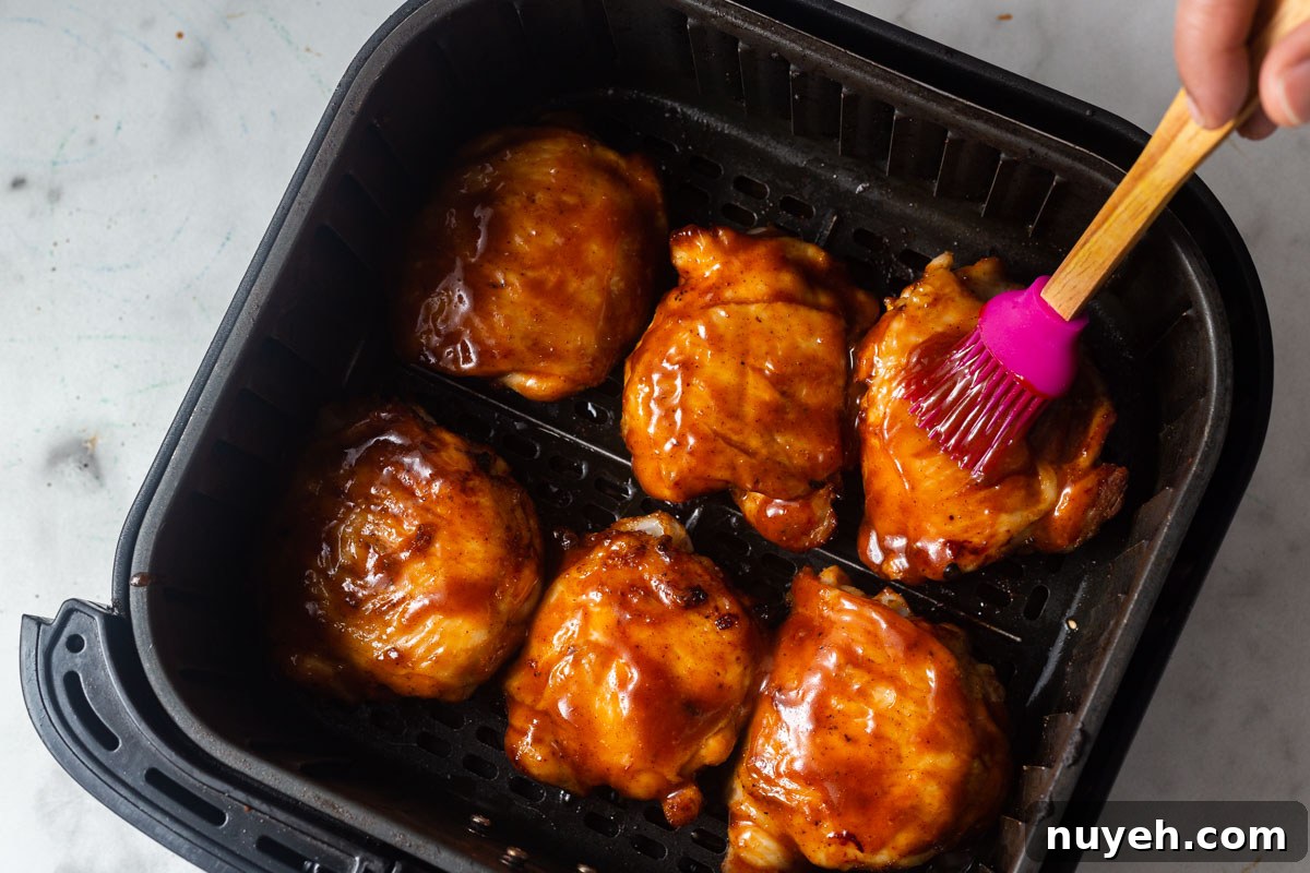 brushing barbecue sauce on chicken thighs.