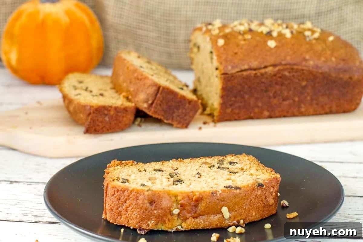 A slice of Dairy-free Pumpkin Bread on a black plate with more in the background.