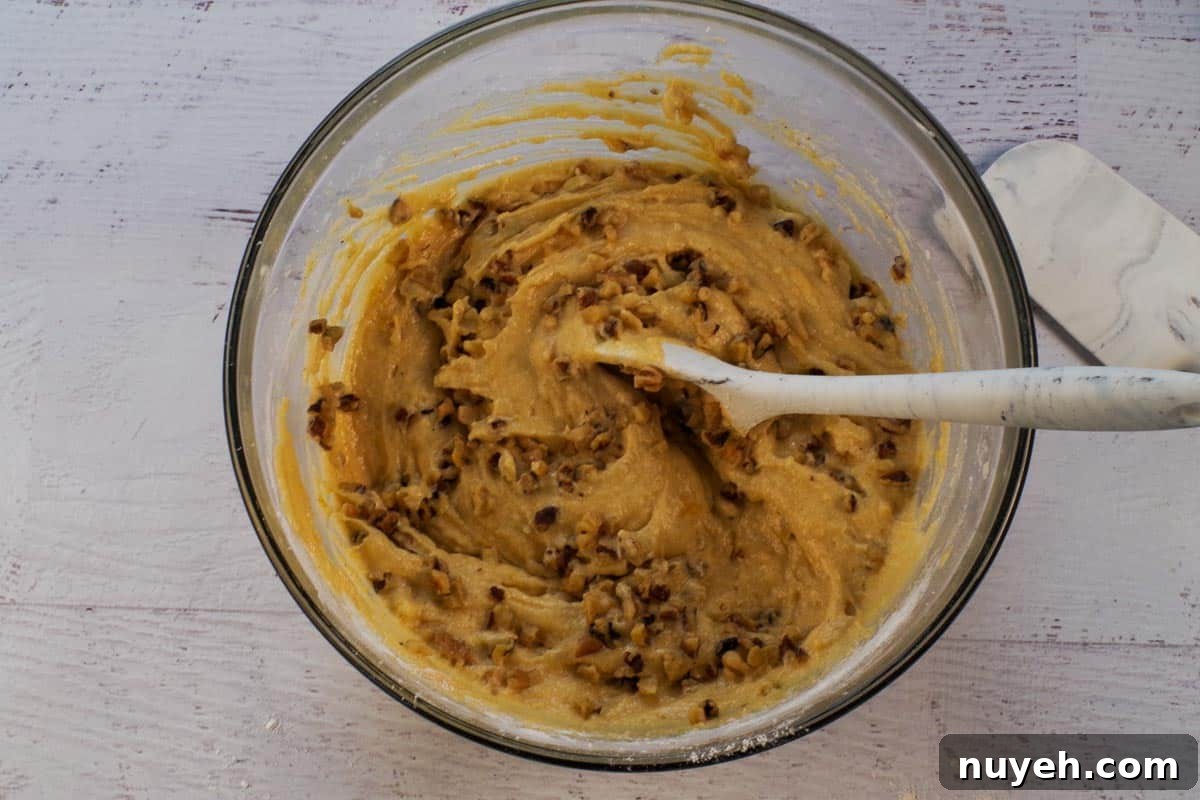 Nuts mixed into pumpkin mixture in large glass bowl.
