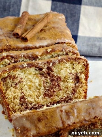 cinnamon loaf on marble cutting board with blue and white checkered tea towel in background