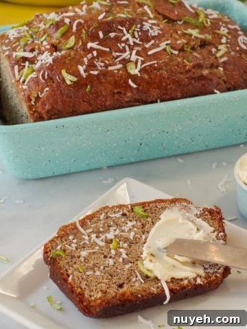 banana bread in blue loaf pan with slice of banana bread on a white plate with butter