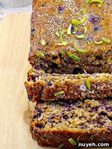 gingerbread loaf on a cutting board with blueberries and limes in background