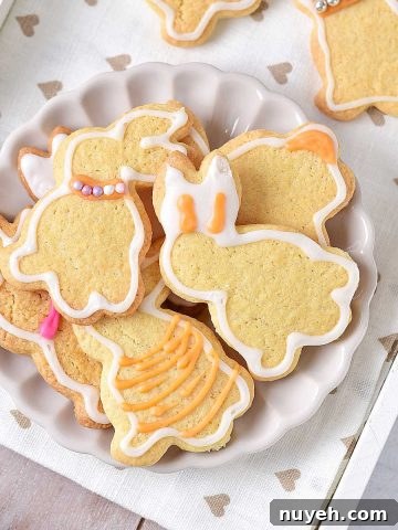 Classic Frosted Sugar Cookies Recipe 15 Overview of white plate with a pile of iced bunny sugar cookies on a white tray with beige hearts.