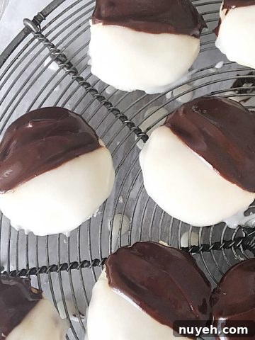 Classic Frosted Sugar Cookies Recipe 16 Several black and white cookies on a round wire rack. View from above.