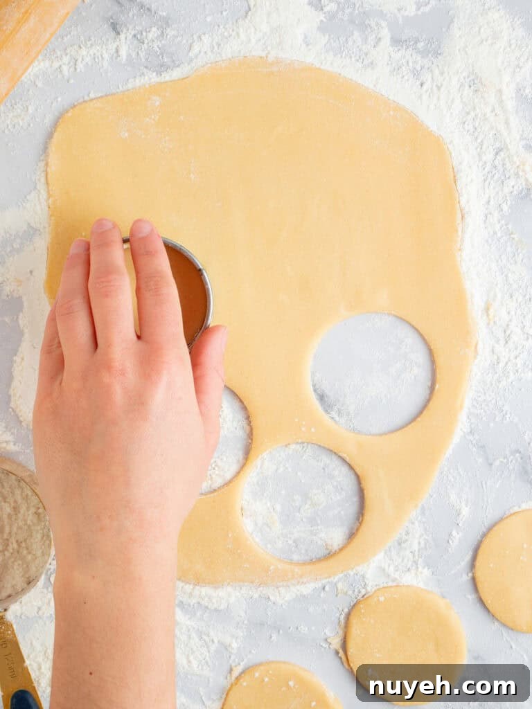 Classic Frosted Sugar Cookies Recipe 6 Cutting round cookies from rolled sugar dough. Floured marble surface.
