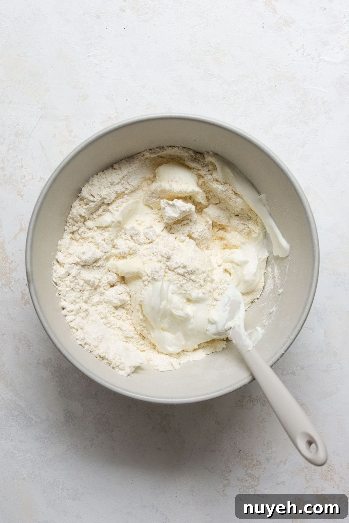 Mixing self-rising flour and Greek yogurt in a bowl to form healthy, high protein pizza dough.