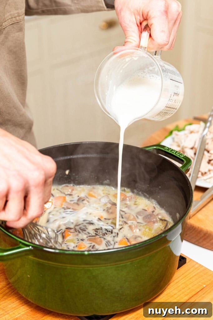 Creamy Chicken and Wild Rice Soup Recipe 11 Adding whole milk and flour mixture to thicken soup in a pot.