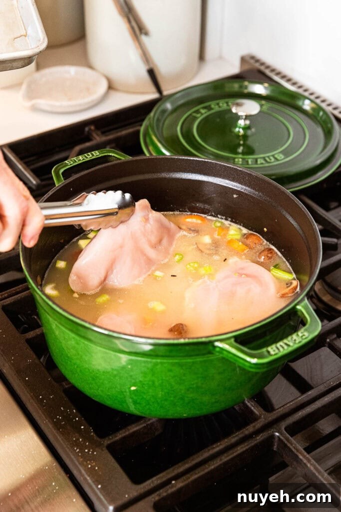 Creamy Chicken and Wild Rice Soup Recipe 8 Placing chicken breast into stock to poach.