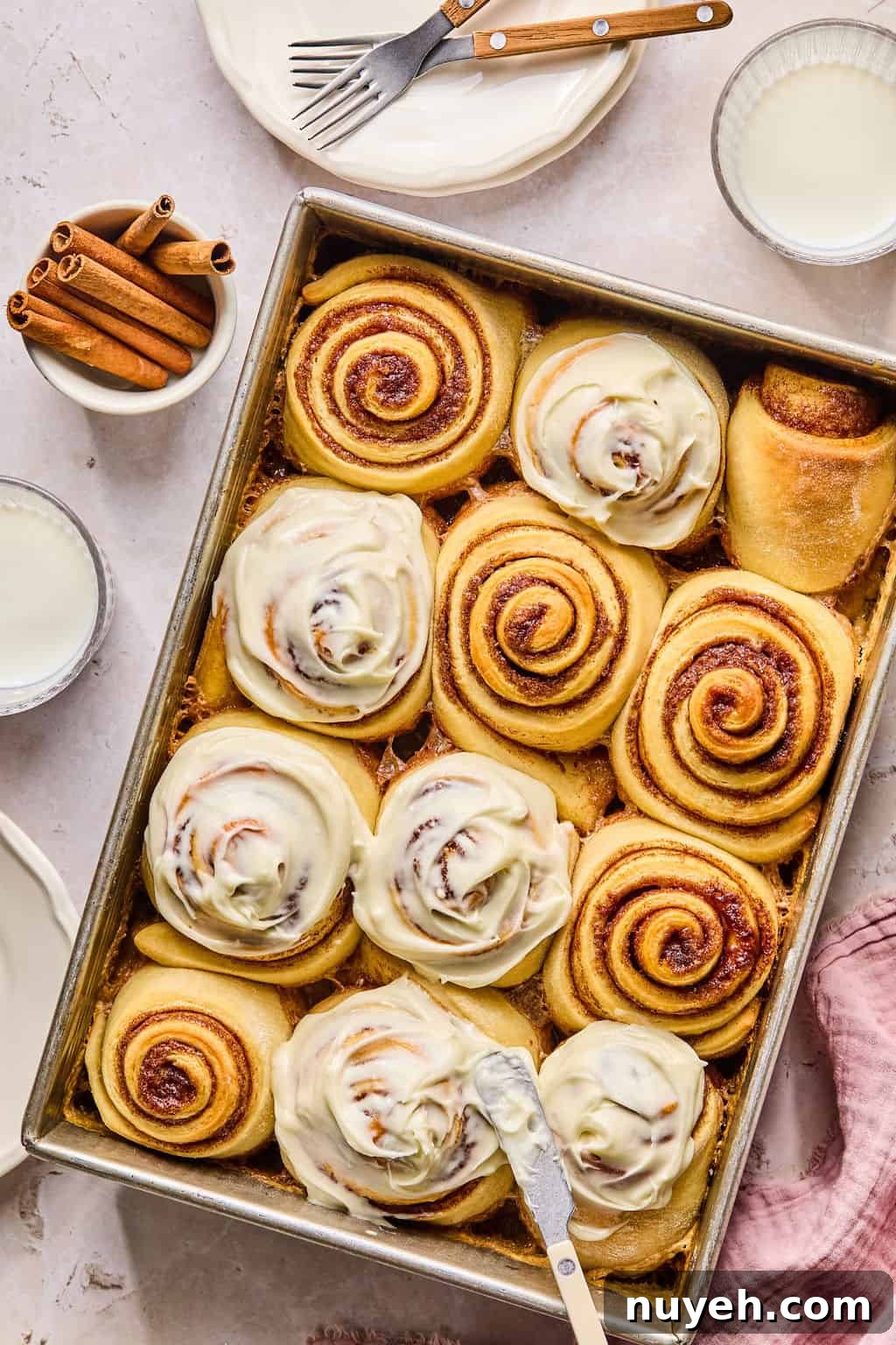 spreading cream cheese frosting on warm cinnamon rolls.