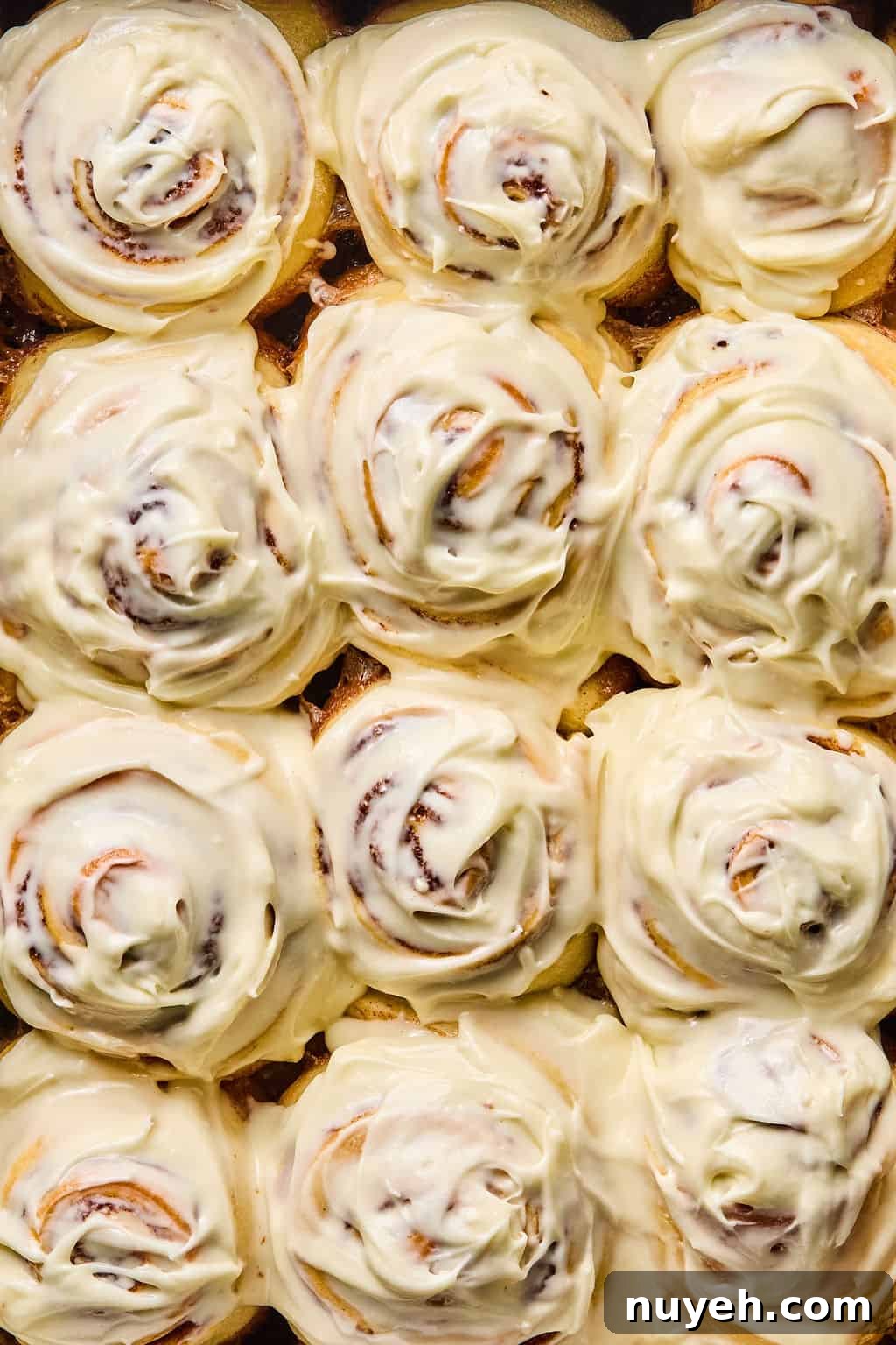 close up photo of gooey soft cinnamon rolls coated in cream cheese frosting.