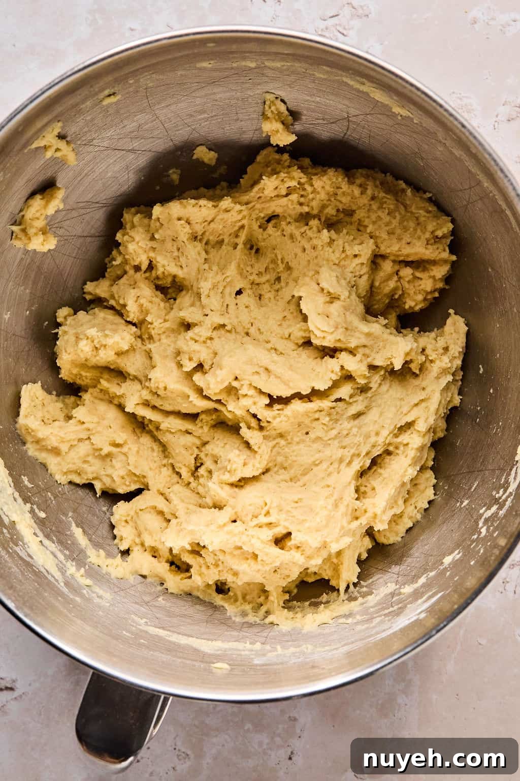 cinnamon roll dough in a stand mixer bowl after combining wet and dry ingredients.