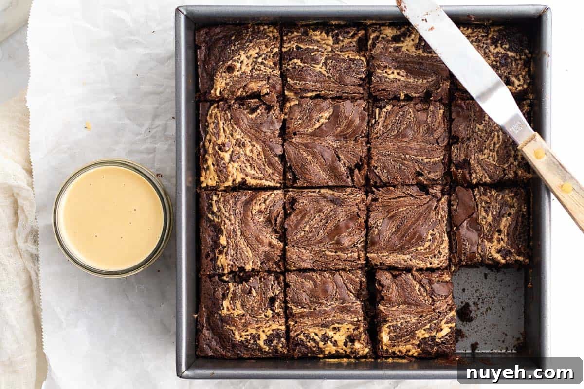 baked tahini brownies in a pan with tahini sauce next to it
