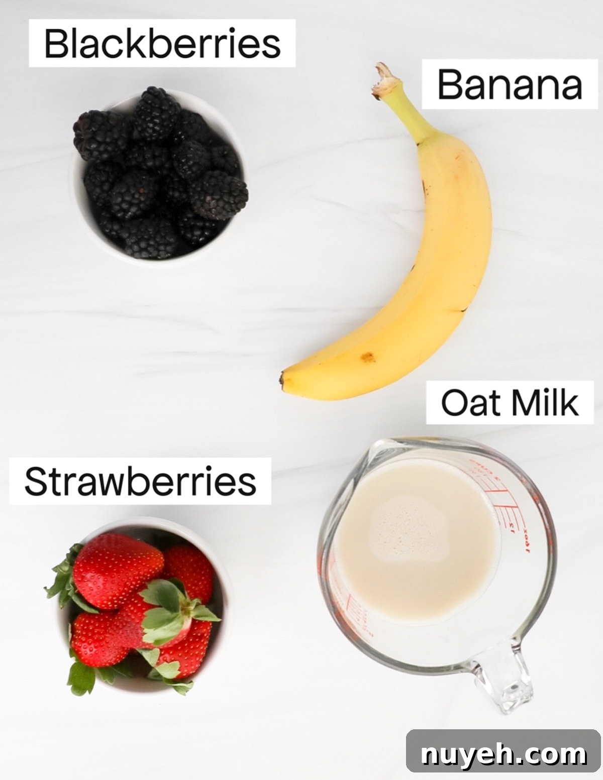 Labeled ingredients including blackberries, a banana, strawberries, and a measuring cup filled with oat milk.