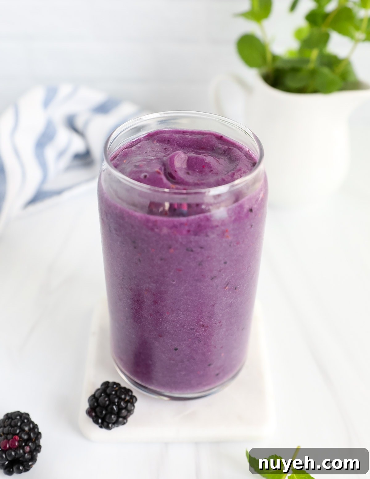 A clear glass filled with a purple smoothie.