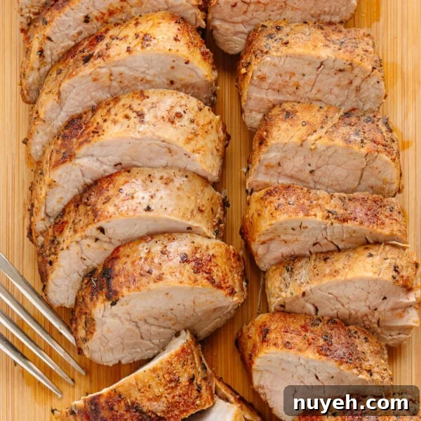 Sliced cast iron pork tenderloin on a wood board with a fork.