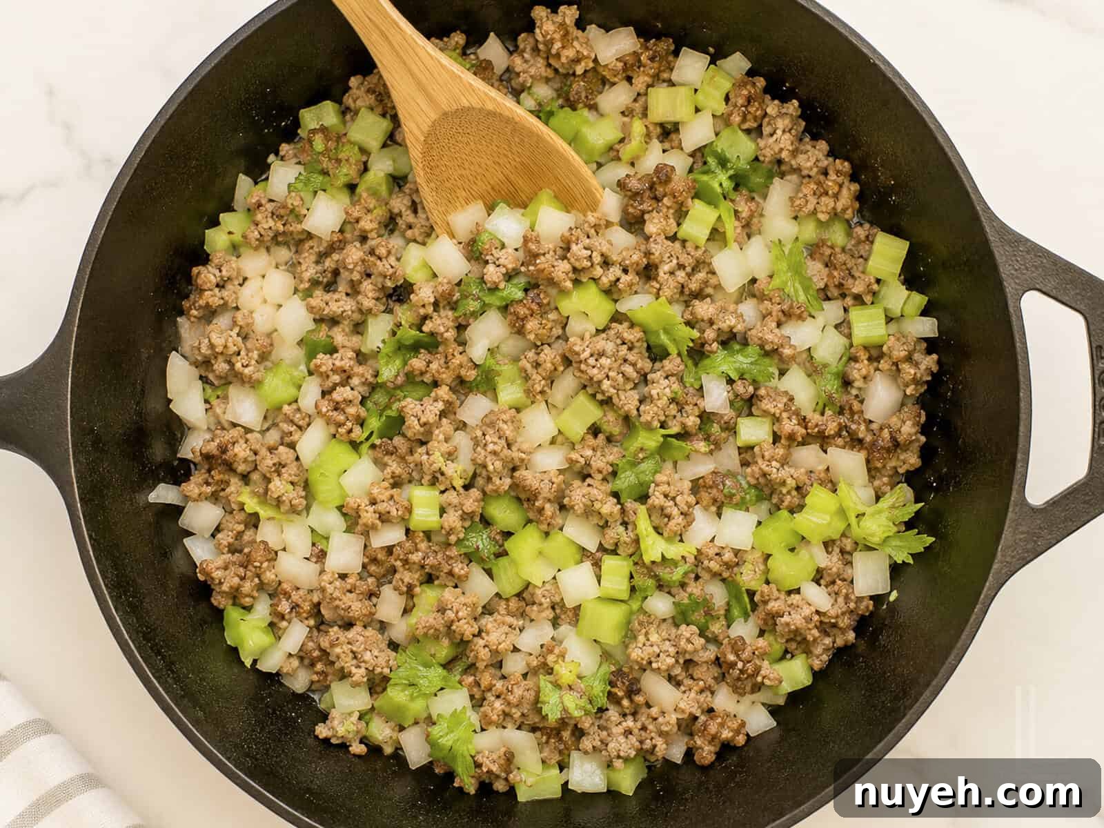 Cooking ground sausage with chopped celery and onions in a skillet for cornbread dressing.