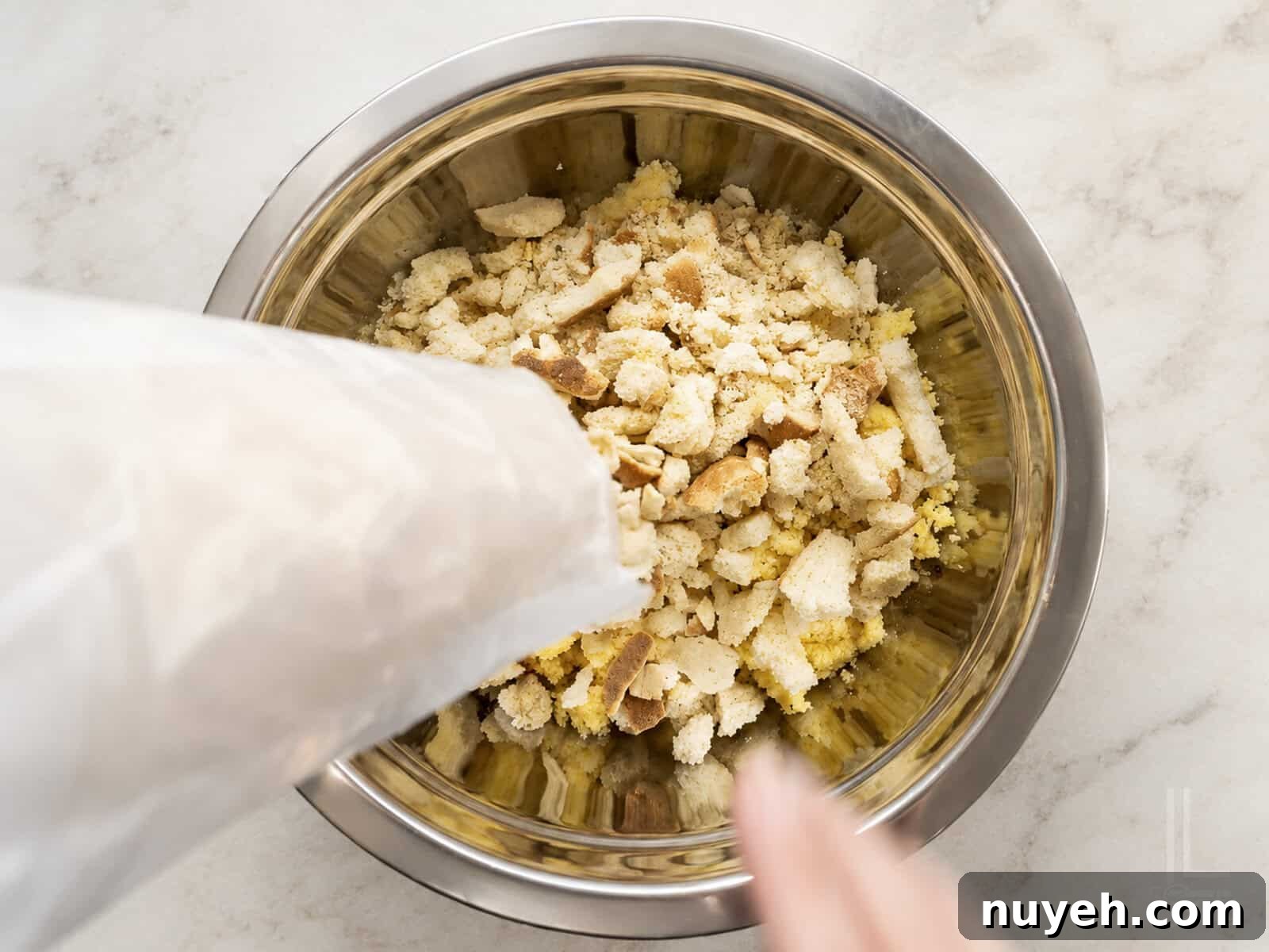 Crumbled cornbread, white bread, and saltines in a metal bowl for dressing.