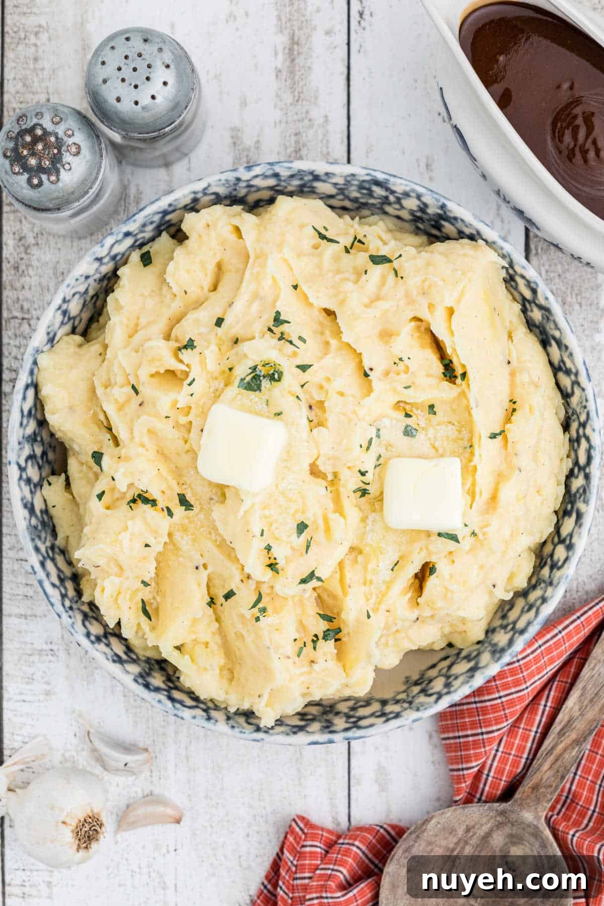 An overhead view of a large bowl of mashed potatoes with some butter melted on top.