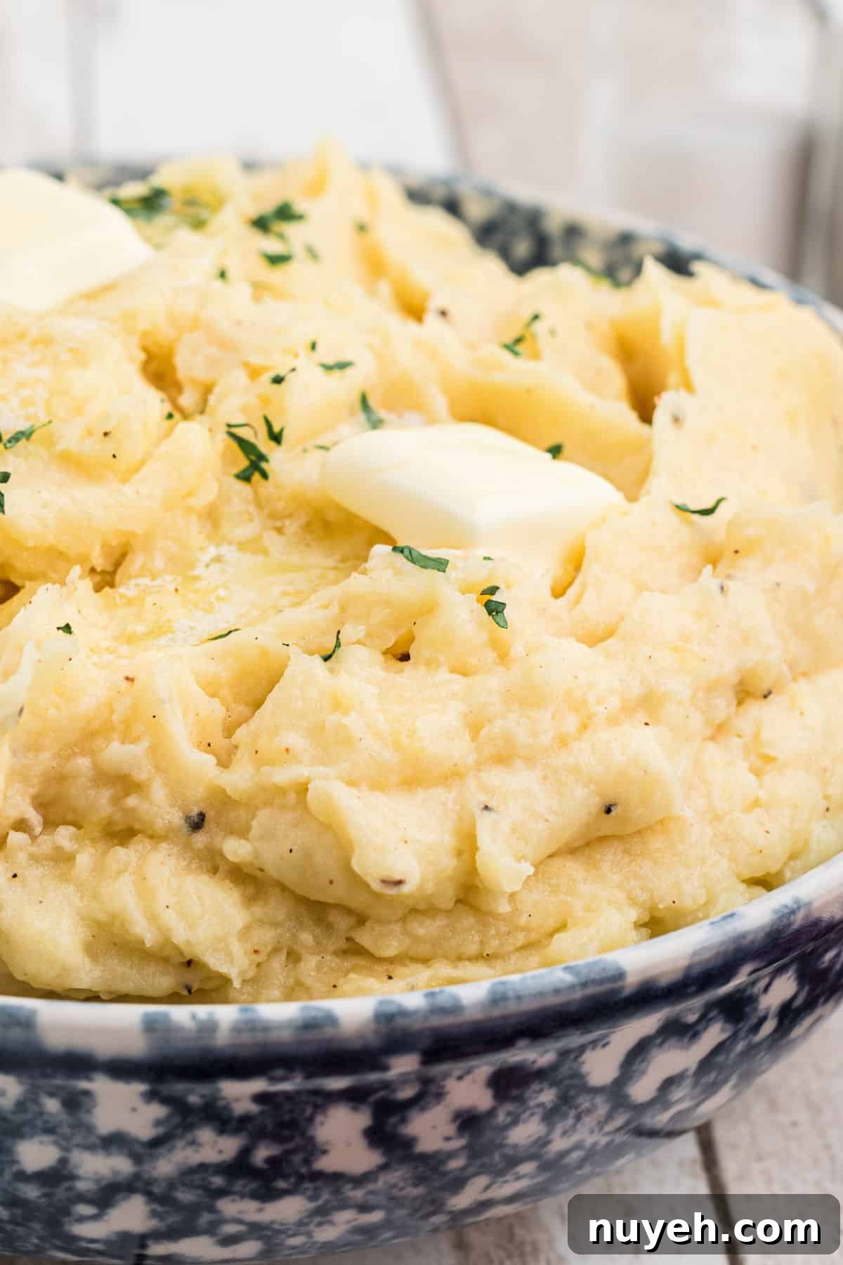 A close up of a large bowl of copycat Popeyes mashed potatoes with some butter melting on top.
