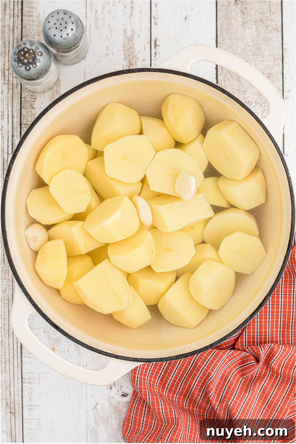 Peeled potatoes and garlic in a large Dutch oven pot.