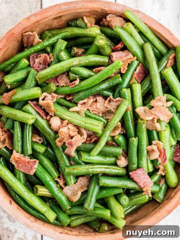 close up of a ceramic bowl full of cajun green beans with bacon