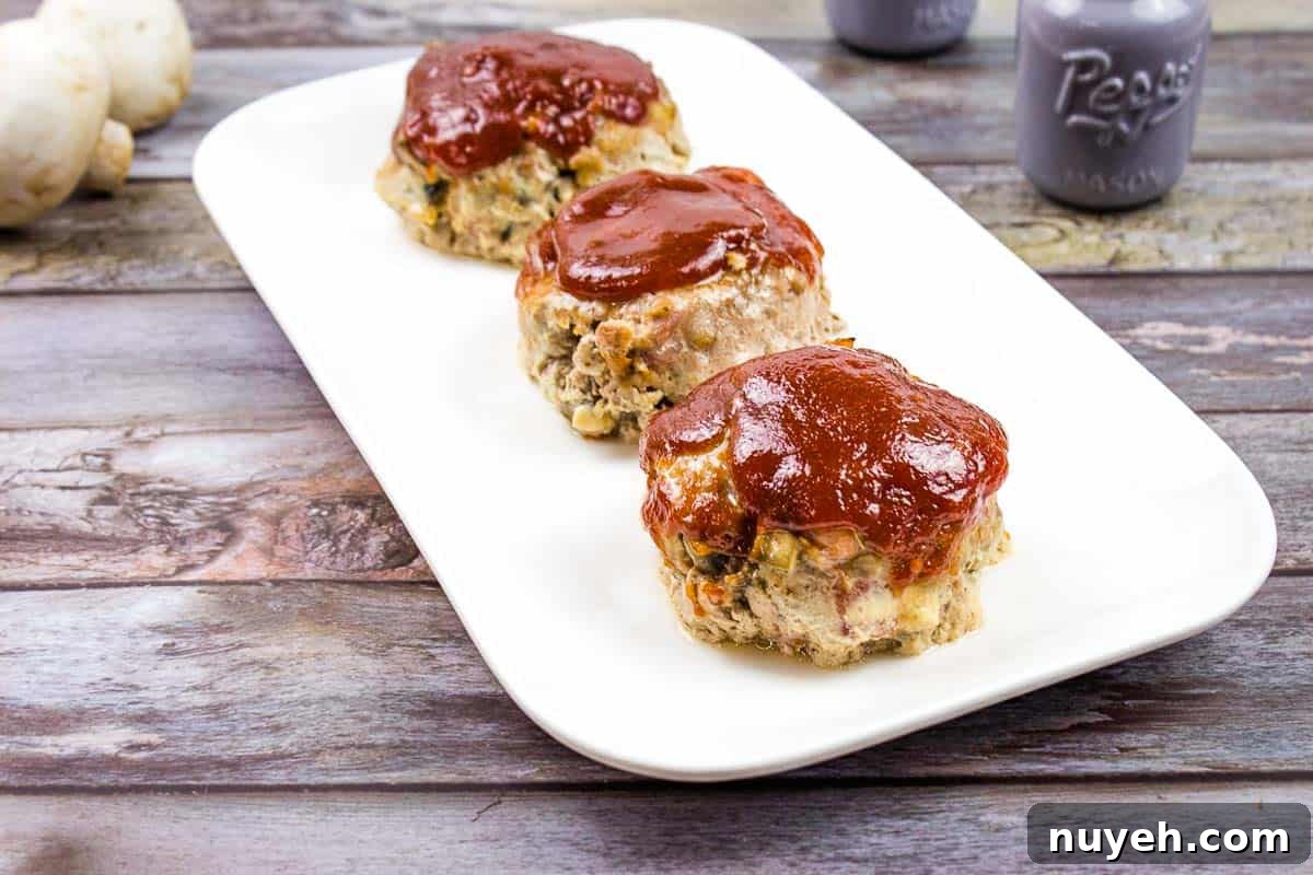 3 Mini Meatloaves in a line on a white plate.