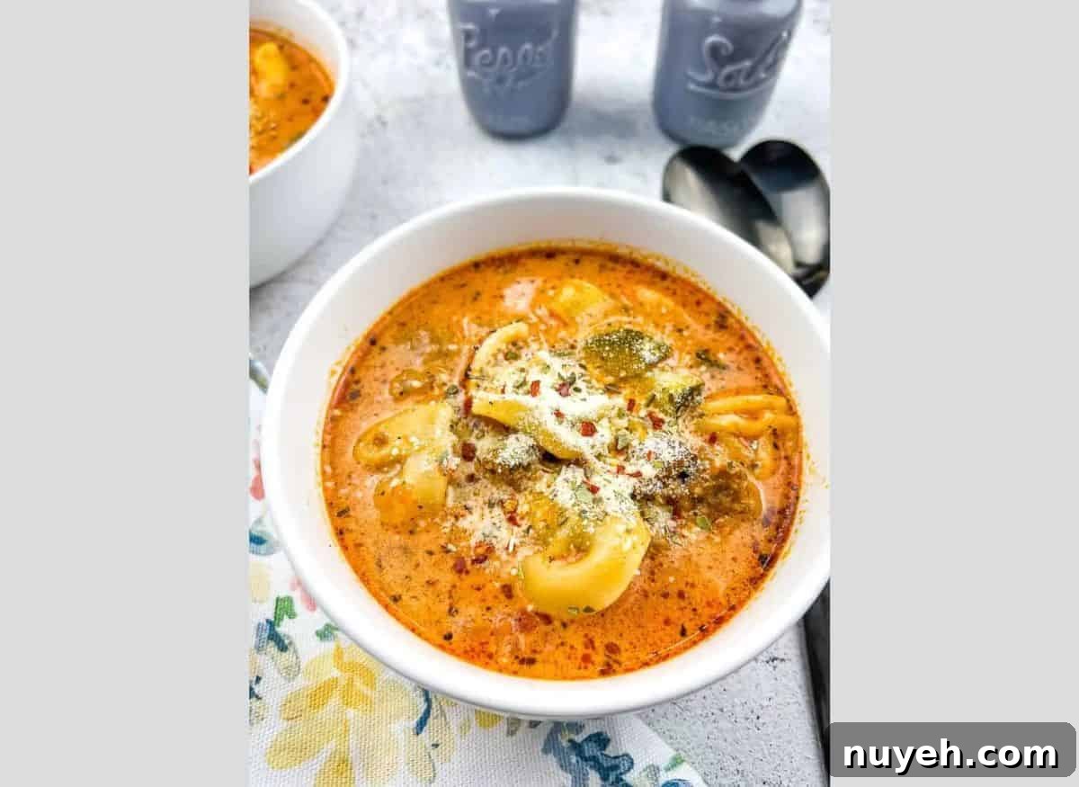Tortellini Soup with Sausage in a white bowl.