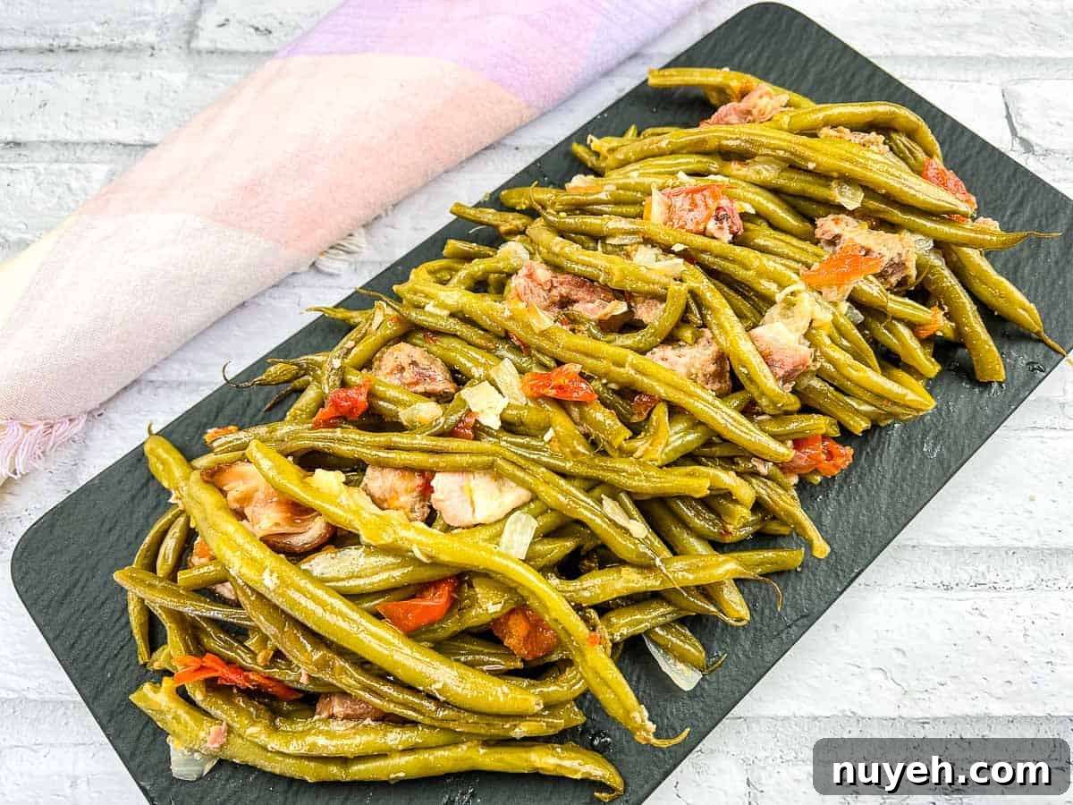 Green beans with pork on a black plate.