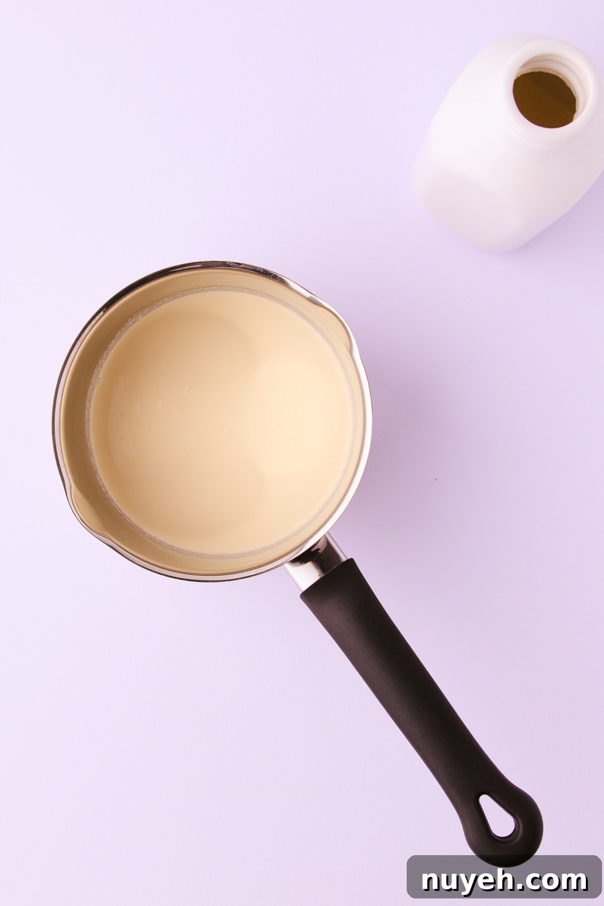 Whipping cream in a black-handled stainless steel saucepan. 