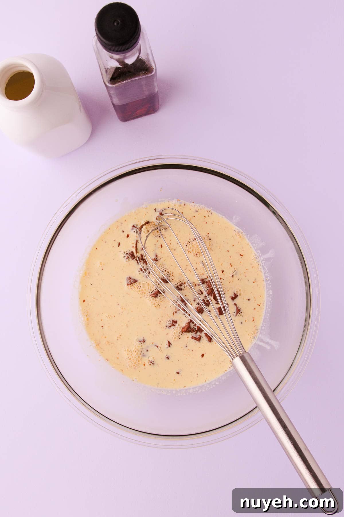 Chopped chocolate and hot cream, in a glass bowl.