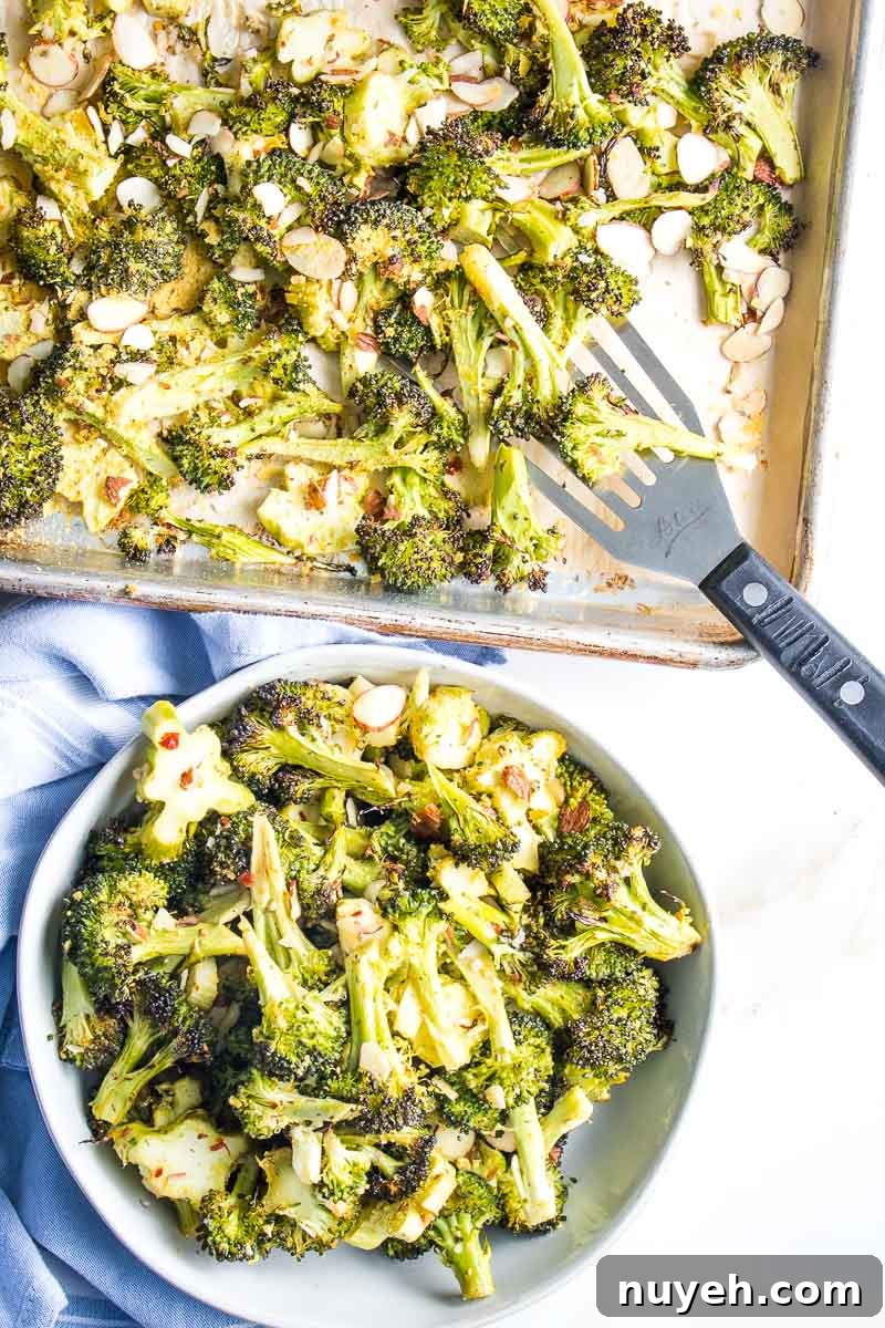 Sheet Pan of roasted broccoli with a spatula loading it into a bowl. 